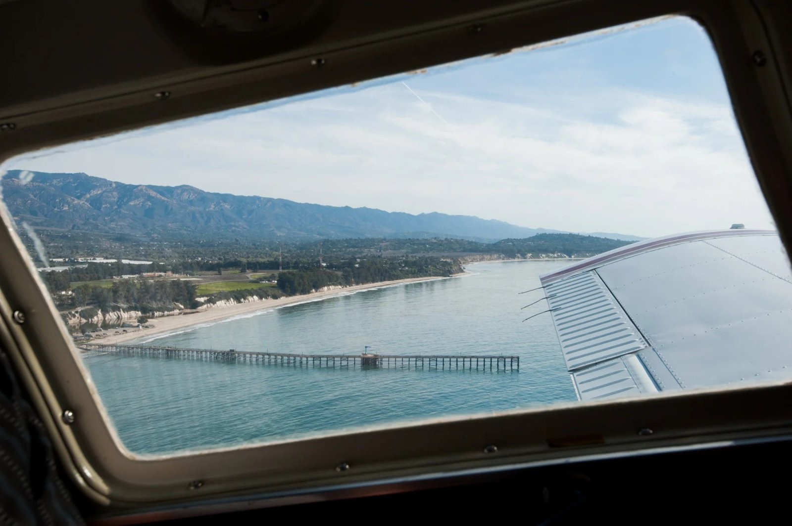 The Santa Barbara coastline and a pier seen through an airplane window
