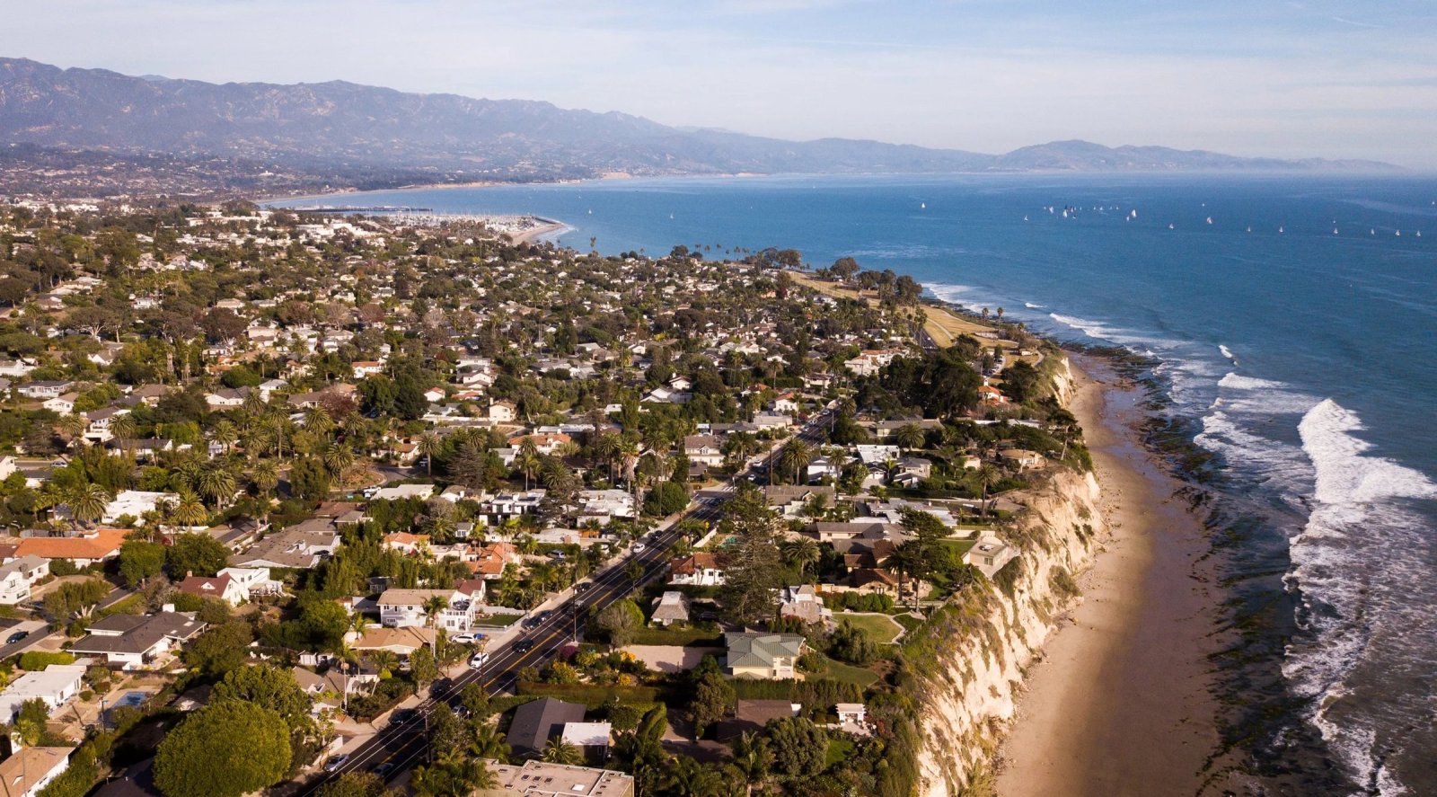 Aerial view of Santa Barbara's bluffs, beach and neighborhoods, with the mountains beyond